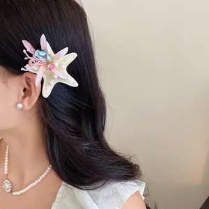 Detailed view of a starfish hair clip with fabric flowers and rhinestones on a model.
