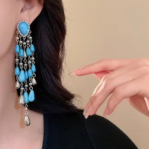 Close-up detail of bohemian turquoise water drop tassel earrings worn by a model