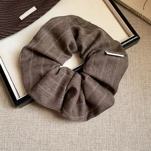Chouchou élégant en tissu à rayures marron présenté dans un décor de style de vie