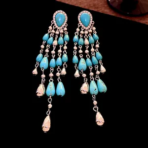 Detailed close-up of long bohemian turquoise teardrop tassel earrings with silver accents
