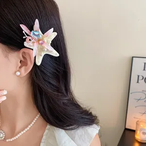 Macro view of a delicate fabric starfish flower hair clip with rhinestones worn by model