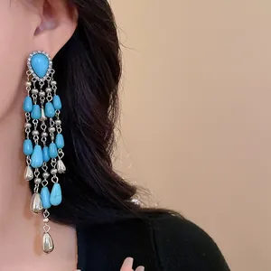 Close-up of bohemian tassel earrings with turquoise teardrop beads and silver accents