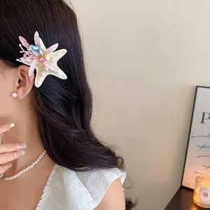 Close-up of elegant starfish hair clip with floral and pearl accents on model
