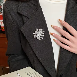 Detailansicht einer eleganten Zirkon-Schneeflockenbrosche mit Perlen auf einem Blazer.