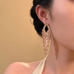 Primo piano dettagliato di orecchini geometrici con nappe di zirconi rosa su modella