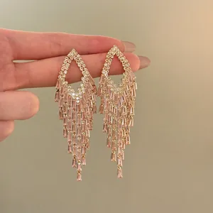 Primo piano di eleganti orecchini dorati con nappine e cristalli champagne