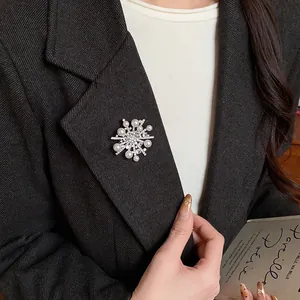 Detailansicht einer exquisiten Zirkon-Schneeflocken-Perlenbrosche auf einem schwarzen Blazer.