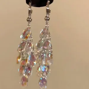 Close-up of ethnic style silver needle earrings with iridescent rhinestone tassels