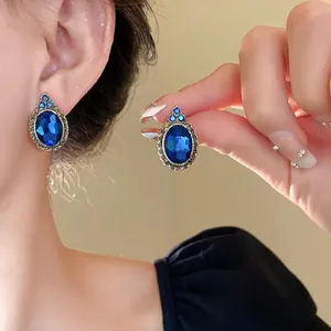 Vintage oval blue gemstone earrings with ornate gold border and teal stone accents
