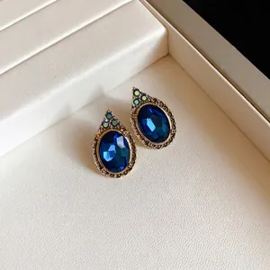 Elegant vintage oval blue crystal earrings with antique gold frame on display tray