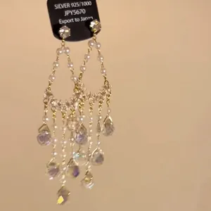 Detailed view of ethnic silver needle earrings with iridescent teardrop crystal tassels