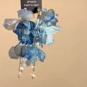 Macro detail of ethnic blue fabric flower tassel earrings with dangling crystals and silver needles