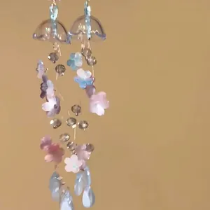 Close-up of delicate floral tassel earrings with colorful beads and flower charms.