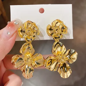 Detailed view of large gold floral drop earrings with textured metallic petals