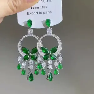 Detailed macro view of vintage ethnic silver earrings featuring green butterfly and tassels.