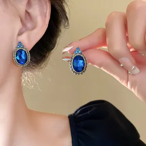 Close-up of elegant oval blue gemstone earrings with ornate silver-tone frame