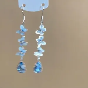 Detailed shot of blue butterfly tassel earrings with water-drop crystal pendants.