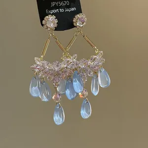 Close-up of elegant ethnic style earrings featuring light blue water-drop tassels and crystals.