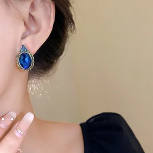 Close-up detail view of vintage royal style oval blue gemstone earring worn on the ear