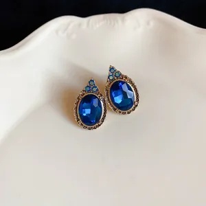 Macro view of vintage royal style earrings with oval blue crystals in gold frame