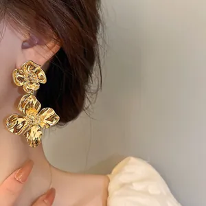 Macro close-up view of large vintage-style gold floral earrings on a model's ear