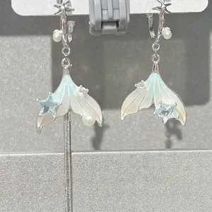 Detailed view of silver mermaid tail earrings featuring pearls and blue star accents.