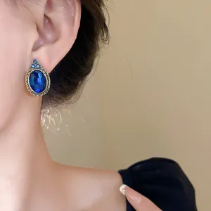 Close-up of vintage blue oval crystal stud earring worn on ear with elegant styling