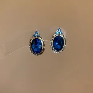 Close-up of vintage style silver stud earrings with oval royal blue gemstones
