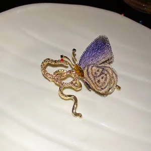 Close-up of vintage butterfly brooch with knitted wing and rhinestone snake design