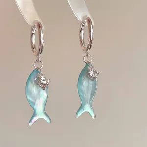 Macro view of blue pearlescent fish earrings with small zircon stone detail
