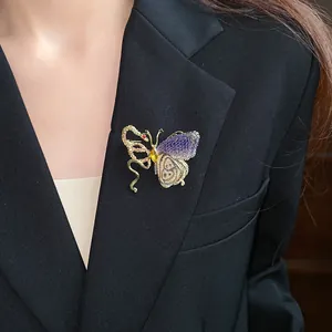 Detailed view of a luxury vintage butterfly and snake brooch pinned on a black blazer jacket