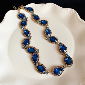 Detailed view of a vintage court style necklace with blue oval gemstones in gold frame
