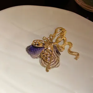 Detail of vintage palace style embroidered butterfly and snake brooch in gold plating