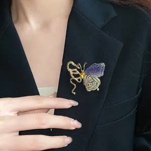 Detail showing a vintage butterfly and snake brooch with knitted texture on black blazer