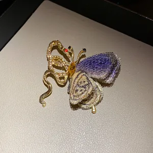 Detailed view of vintage butterfly snake brooch with rhinestones and knit wing