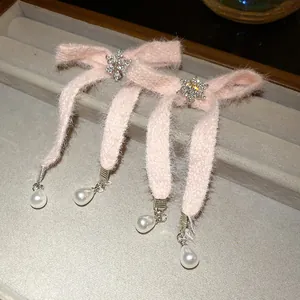 Close-up of pink fuzzy bow hair clips with rhinestone snowflakes and pearl drops