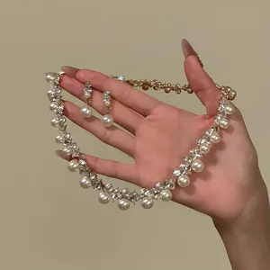 Elegantes französisches Schmuckset mit Perlenhalskette und Kristallohrringen in der Hand
