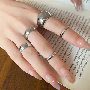 Detailed view of 5-piece minimalist silver metal ring set on hand over book background.
