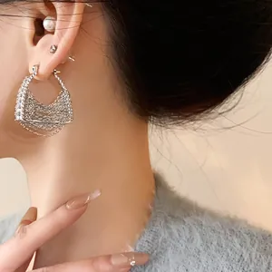 Dettaglio ravvicinato di un orecchino nappa in argento a forma di borsa con zirconi
