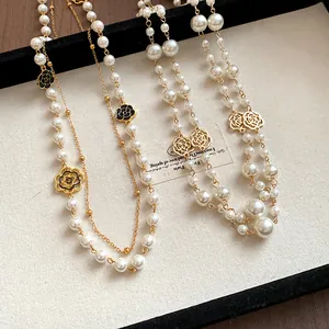 Macro view of double-layered pearl necklaces with black and gold camellia flower charms.