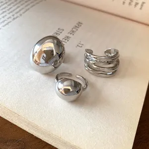 Detailed view of three minimalist silver-tone rings displayed on an open book