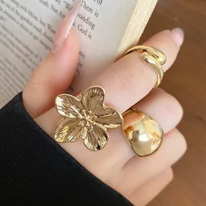 Close-up of a minimalist gold-tone floral ring and chunky dome ring set on hand