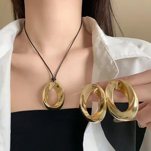 Detailed view of minimalist gold twisted oval pendant necklace and matching earrings set