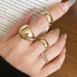 Detailed view of hand wearing a set of five minimalist chunky and thin gold rings
