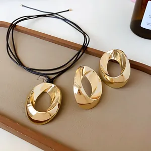 Detailed view of gold twisted oval necklace and earring set on a display tray