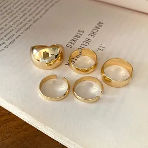 Close-up detail of 5-piece minimalist gold-finished open rings on a vintage book