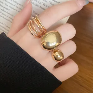 Macro view of chunky gold minimalist open rings with a smooth polished metallic finish.