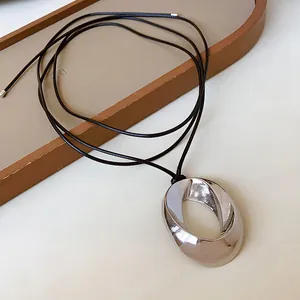 Detailed macro view of minimalist silver oval pendant necklace with elegant black cord