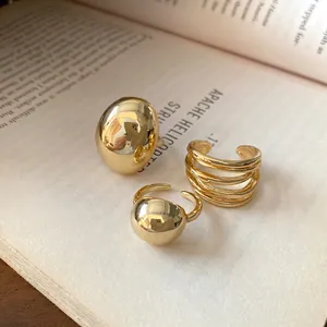 Macro shot of three minimalist gold-toned open rings displayed on an open book.