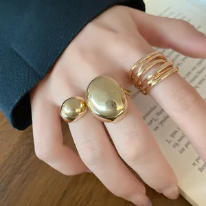 Close-up detail showing the polished gold texture of minimalist metallic open rings set